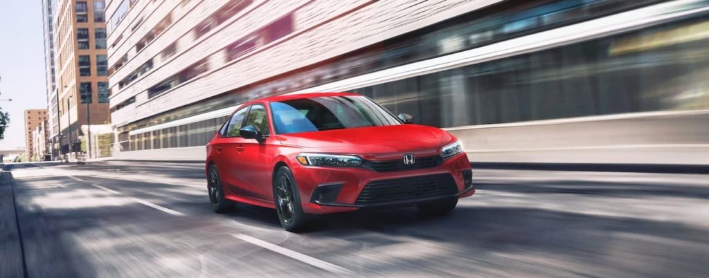 A popular used car for sale, a red 2022 Honda Civic Touring, driving on a city street.