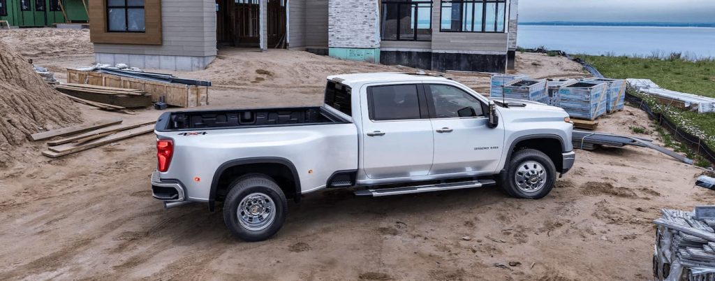 A silver Chevy Silverado 3500 HD parked by a worksite.