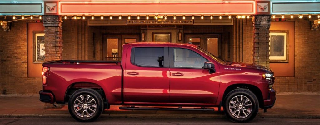 Side view of a red 2024 Chevy Silverado 1500 parked on a street.