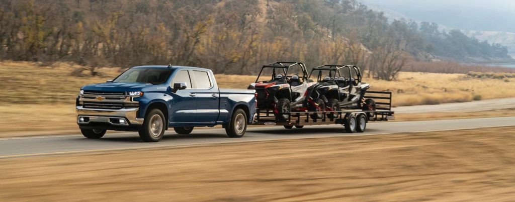 A blue Chevy Silverado 1500 towing a pair of ATVs.