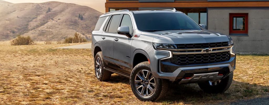 A silver Chevy Tahoe parked in front of a house.
