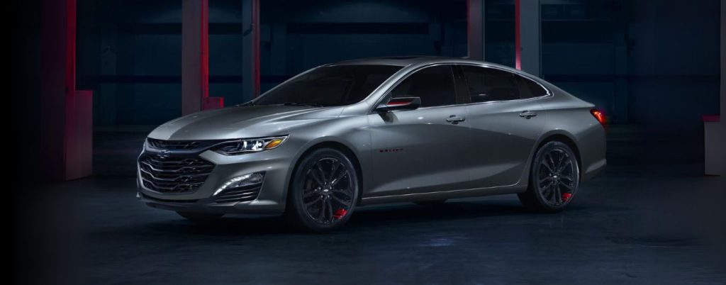 A silver Chevy Malibu parked in a dark room.