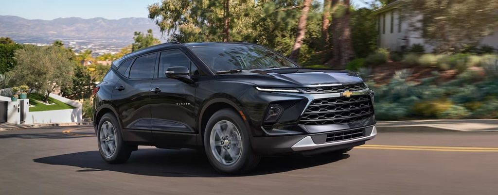 A black 2025 Chevy Blazer driving near a city.