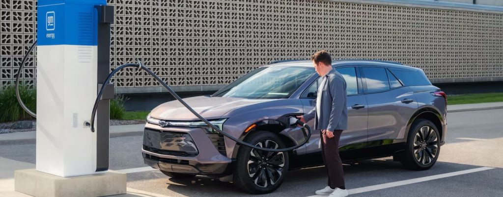 Side view of grey Chevy Equinox EV at a charging station.