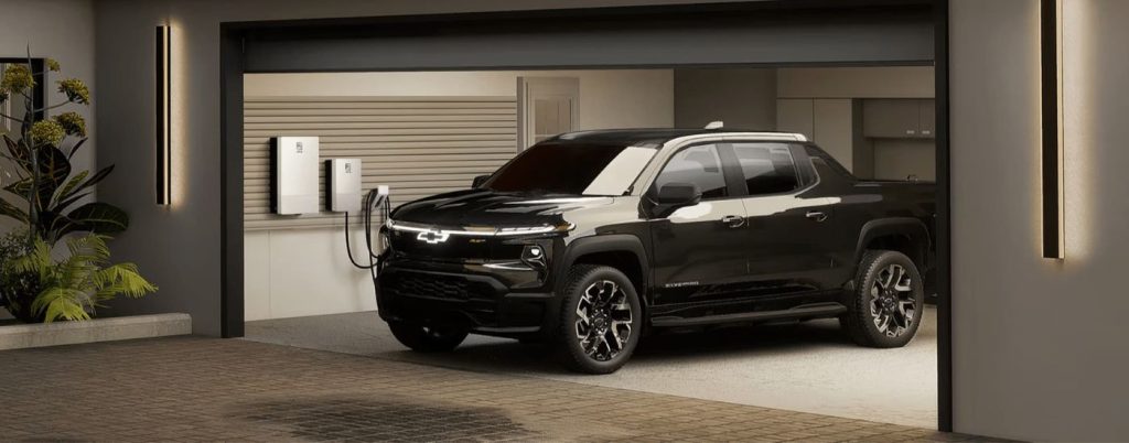 Side view of black Chevy Silverado EV charging in a garage.