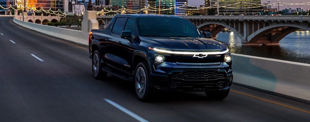 Black Silverado EV driving over a river.