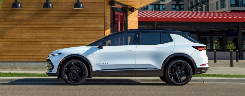 White Chevy Equinox EV parked beside a building.