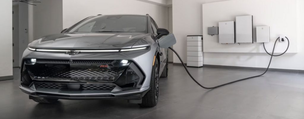 A grey 2025 Chevy Equinox EV plugged into a charger.