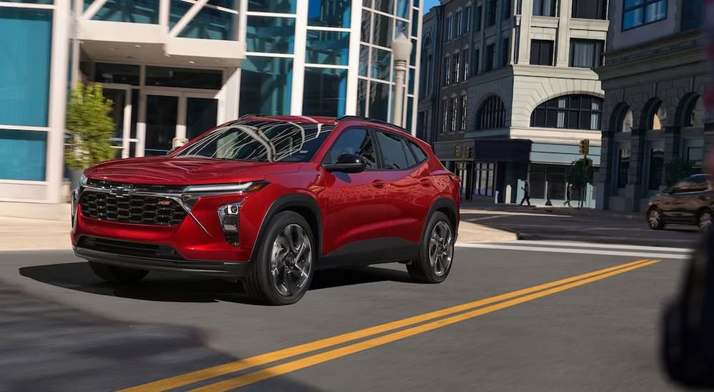 A red 2024 Chevy Trax RS is shown driving on a city street after leaving a Chevy dealer near Converse.