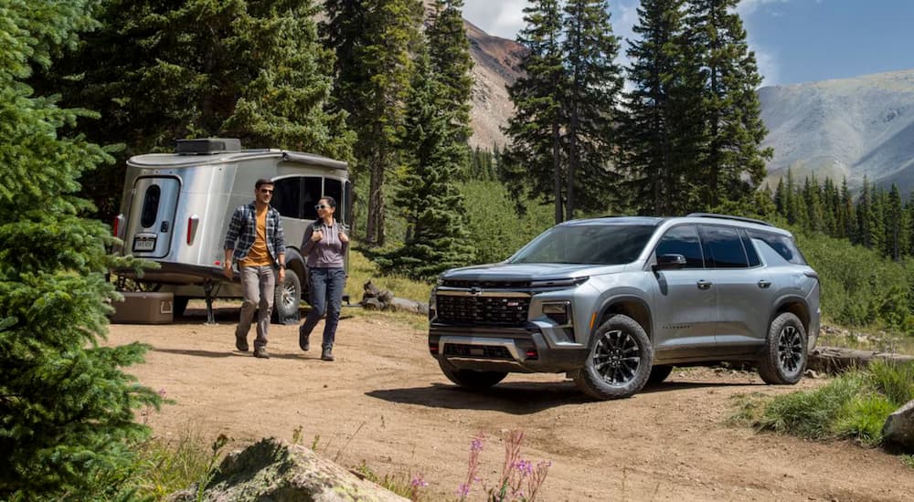 People walking towards a grey 2025 Chevy Traverse for sale parked outside a camper.