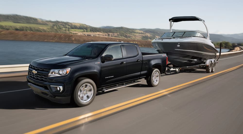 A black 2022 Chevy Colorado is shown from the side towing a boat after searching for used Chevy trucks.