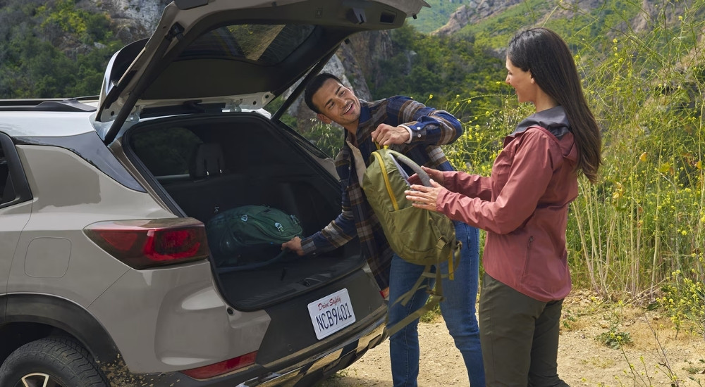 People retrieving backpacks from the rear of a grey 2026 Chevy Trailblazer.