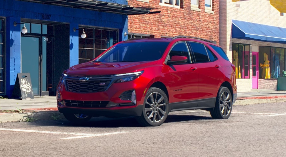 A red 2024 Chevy Equinox RS parked in front of a coffee shop.