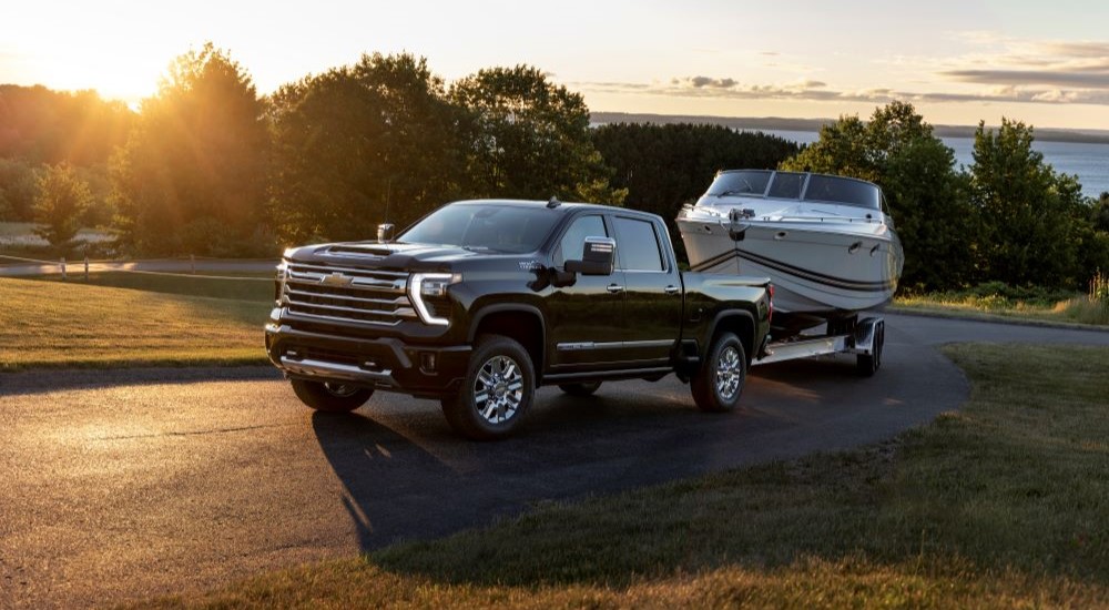 A black 2025 Chevy Silverado 2500 HD High Country towing a boat