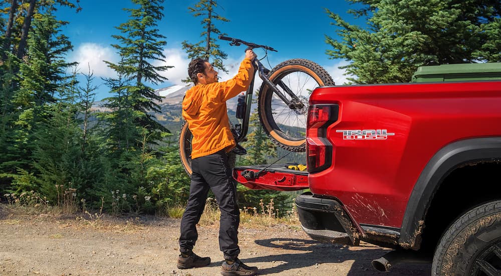 A man taking a bike out of the bed of a red 2025 Chevy Colorado TrailBoss
