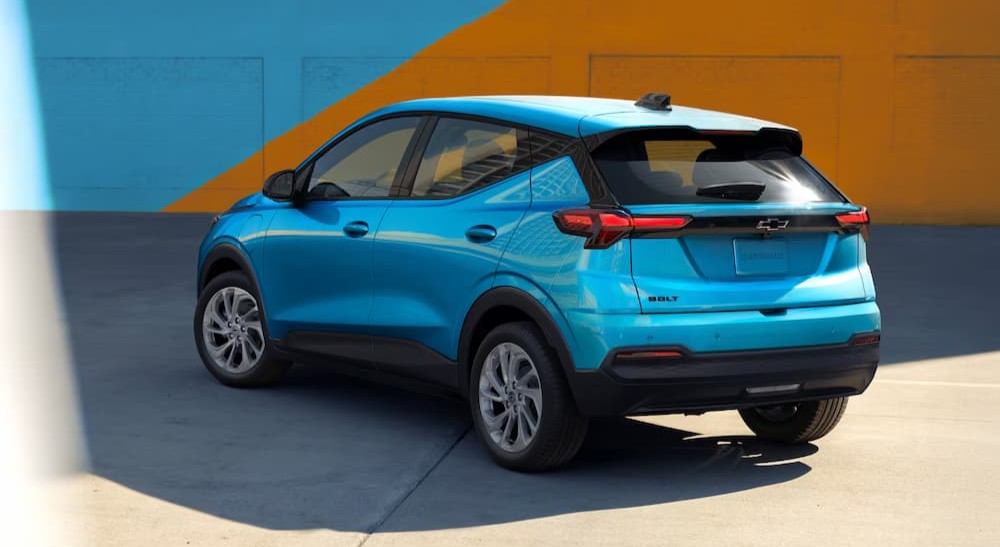 A blue 2027 Chevy Bolt parked in a city.