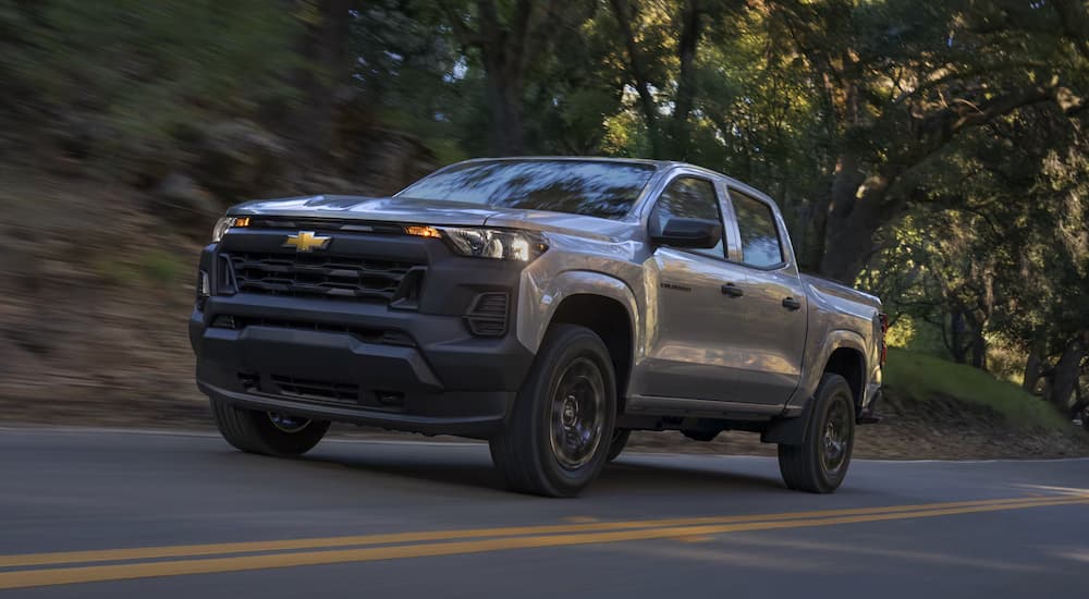 Grey 2026 Chevy Colorado driving on a tree-lined road