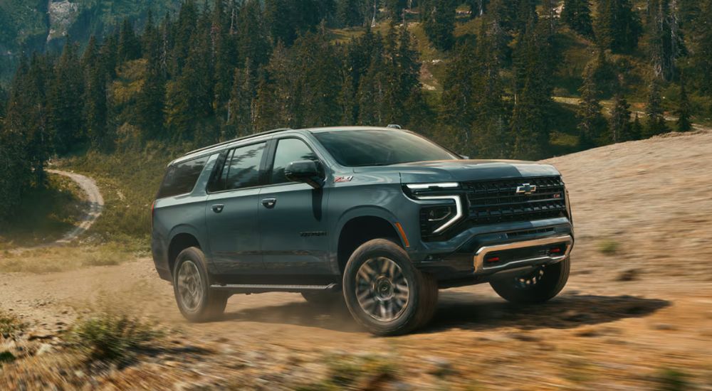 Green 2026 Chevy Suburban off road on a trail.