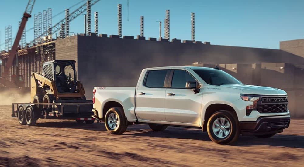 A white 2026 Chevy Silverado 1500 towing a trailer.