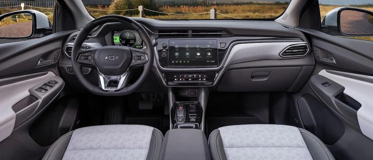 The grey interior of a 2022 Chevy Bolt EUV shows the steering wheel and infotainment screen.