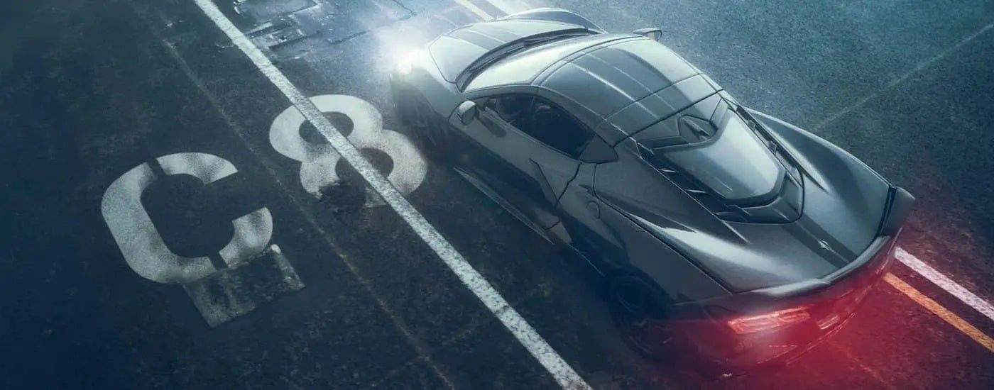 A grey 2022 Chevy Corvette is passing 'C8' markings on asphalt.