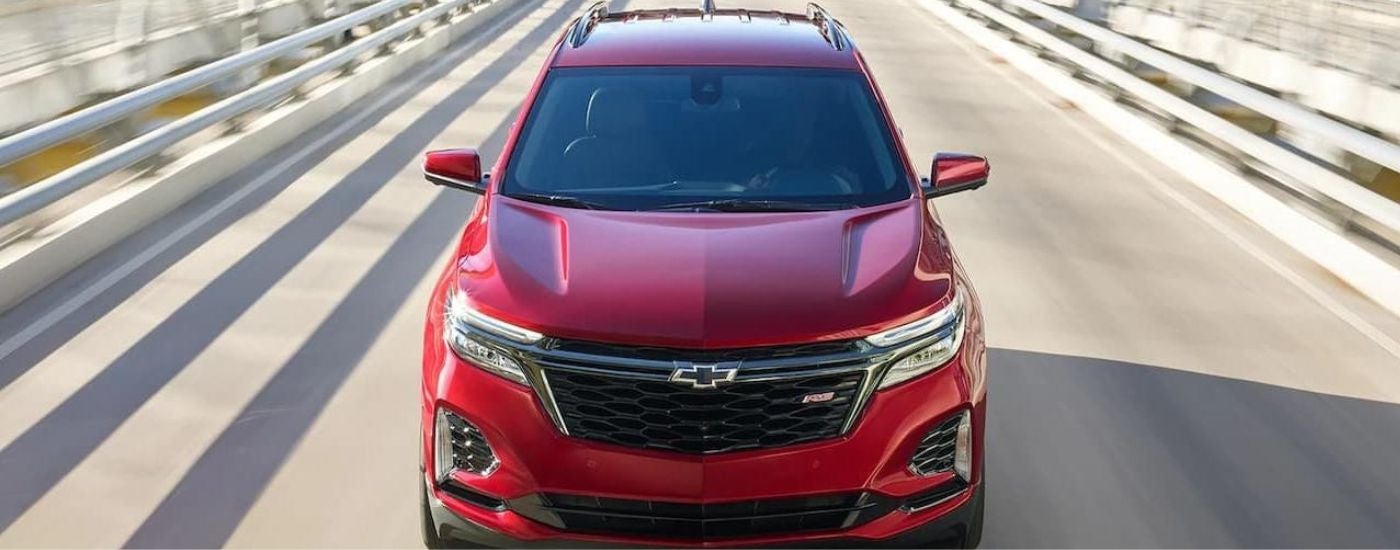 A red 2022 Chevy Equinox RS driving on a bridge.