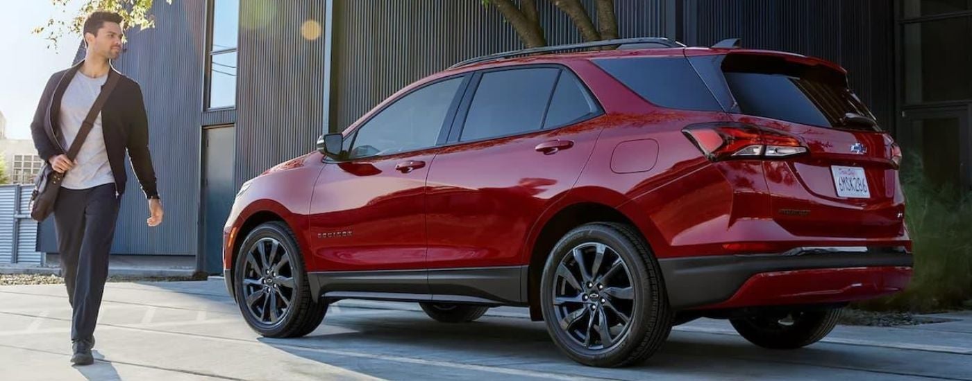 A person walking near a red 2022 Chevy Equinox RS.