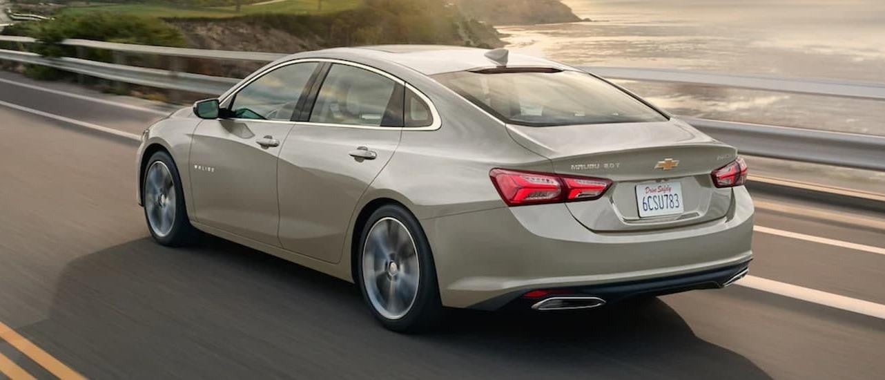 A silver 2022 Chevy Malibu driving past a body of water.