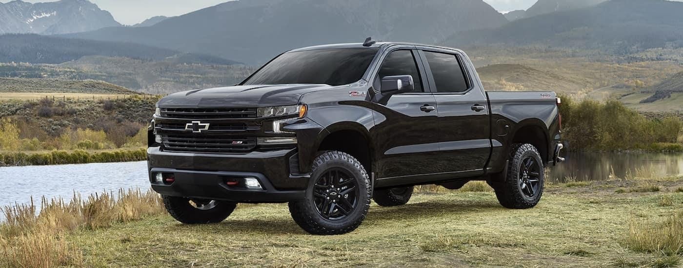 A black 2022 Chevy Silverado 1500 is shown from the side in a field during a 2022 Chevy Silverado 1500 vs 2022 Ram 1500 comparison.