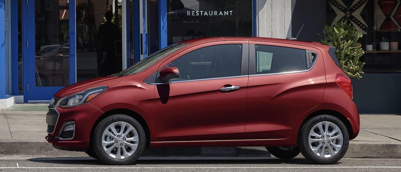 A red 2022 Chevy Spark is shown from the side parked on a city street.