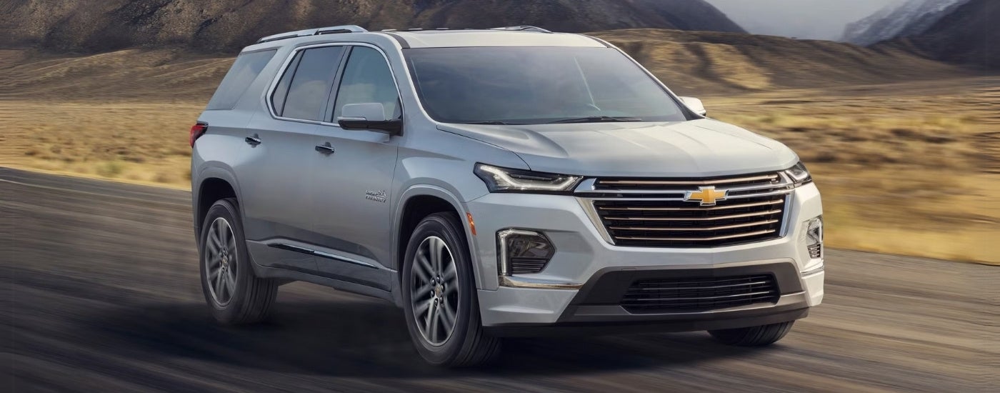 A white 2022 Chevy Traverse High Country driving past distant mountains.