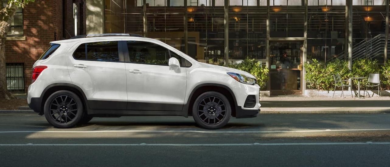 The white 2022 Chevy Trax is shown from the side driving on a city road.