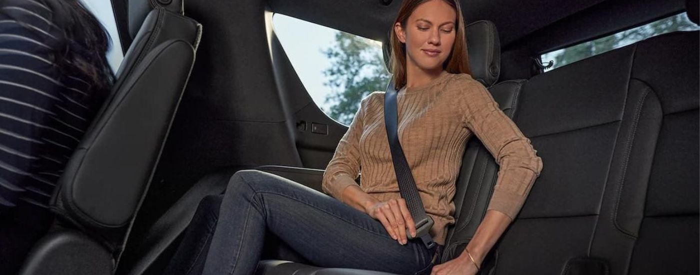 A woman buckling a seat belt in a 2022 Chevy Tahoe.