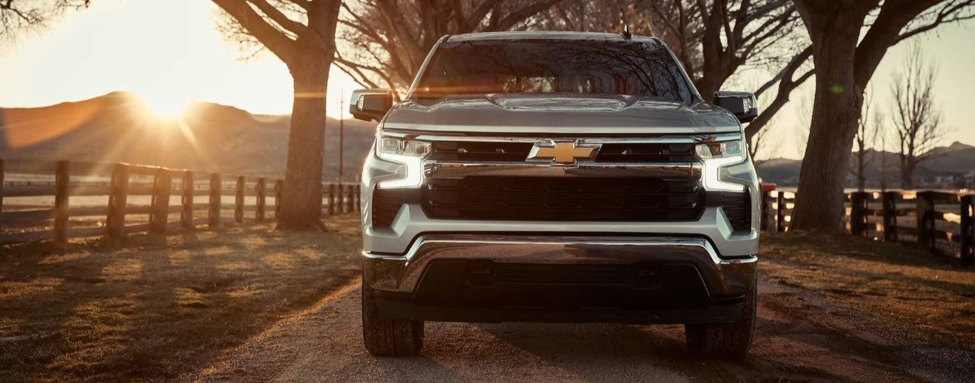 Silver 2023 Chevy Silverado 1500 driving head on at sunset