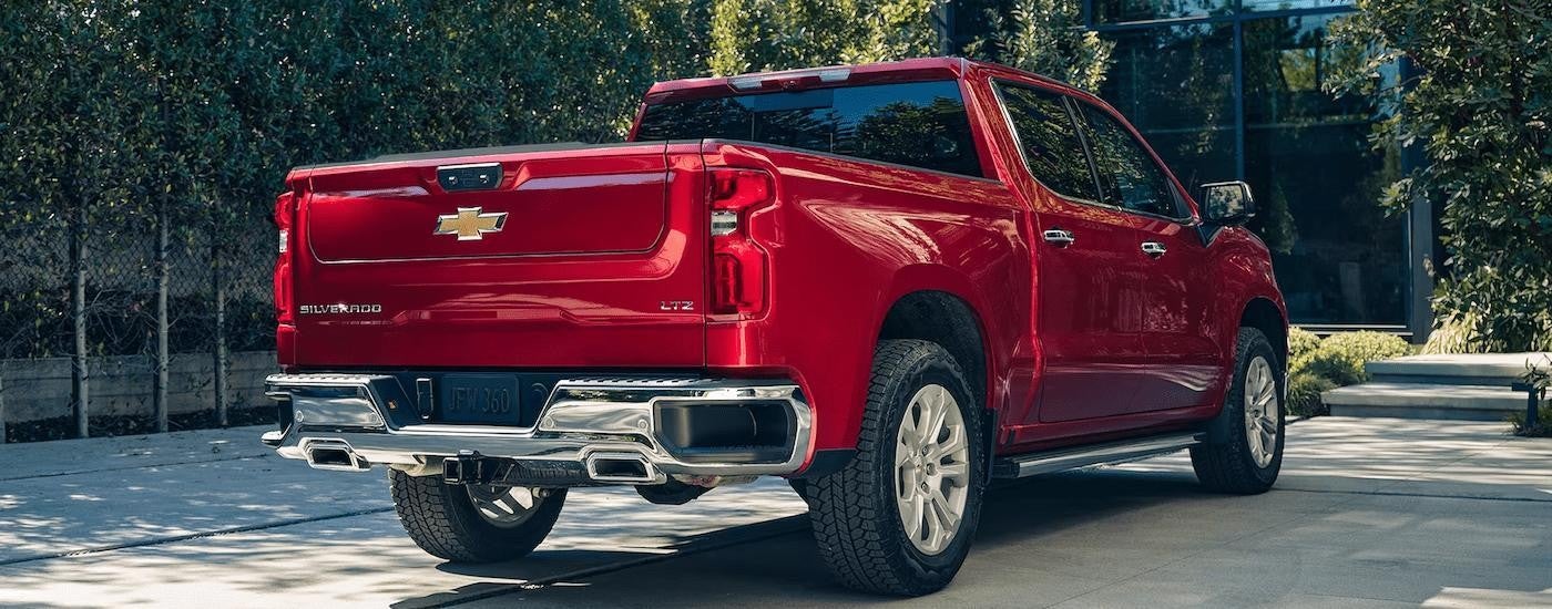 A red 2023 Chevy Silverado 1500 LTZ is shown from a rear angle parked on a concrete driveway.
