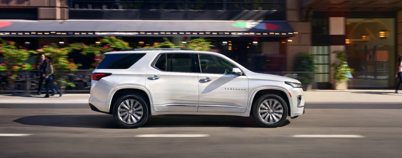A white 2023 Chevy Traverse driving through a city.