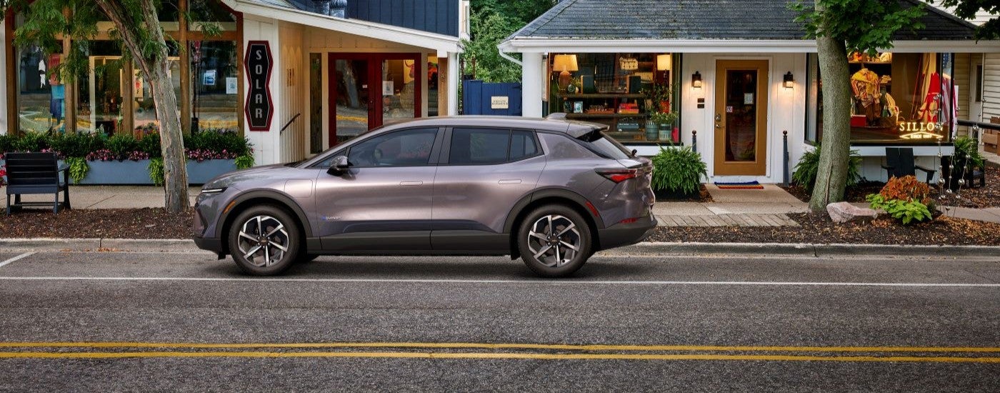 A grey 2024 Chevy Equinox EV parked outside of a shop.