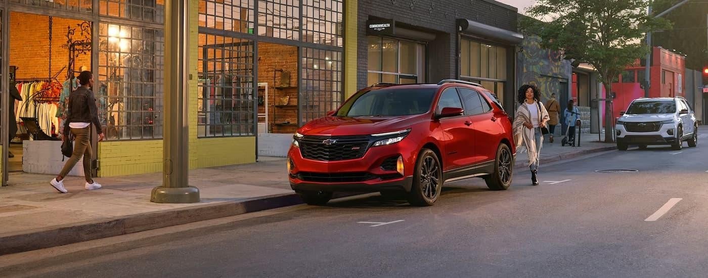A red 2024 Chevy Equinox RS is shown parked on the side of a city street.