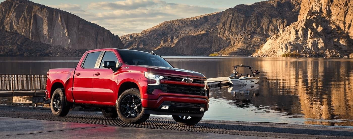 A red 2024 Chevy Silverado 1500 LTZ Z71 is shown parked at a boat launch.