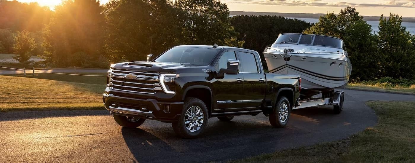 A black 2024 Chevy Silverado 2500 HD High Country towing a boat.