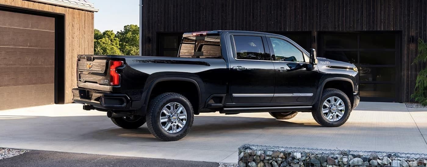 A black 2024 Chevy Silverado 2500 HD High Country parked on a driveway.