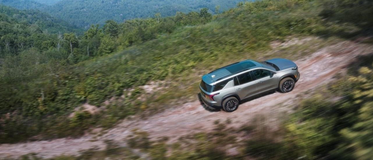 A silver 2024 Chevy Traverse Z71 is shown driving on a mountain trail.