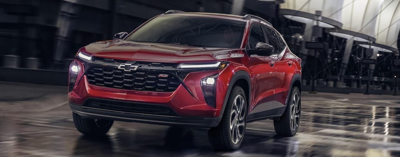 A red 2024 Chevy Trax RS driving in a city.