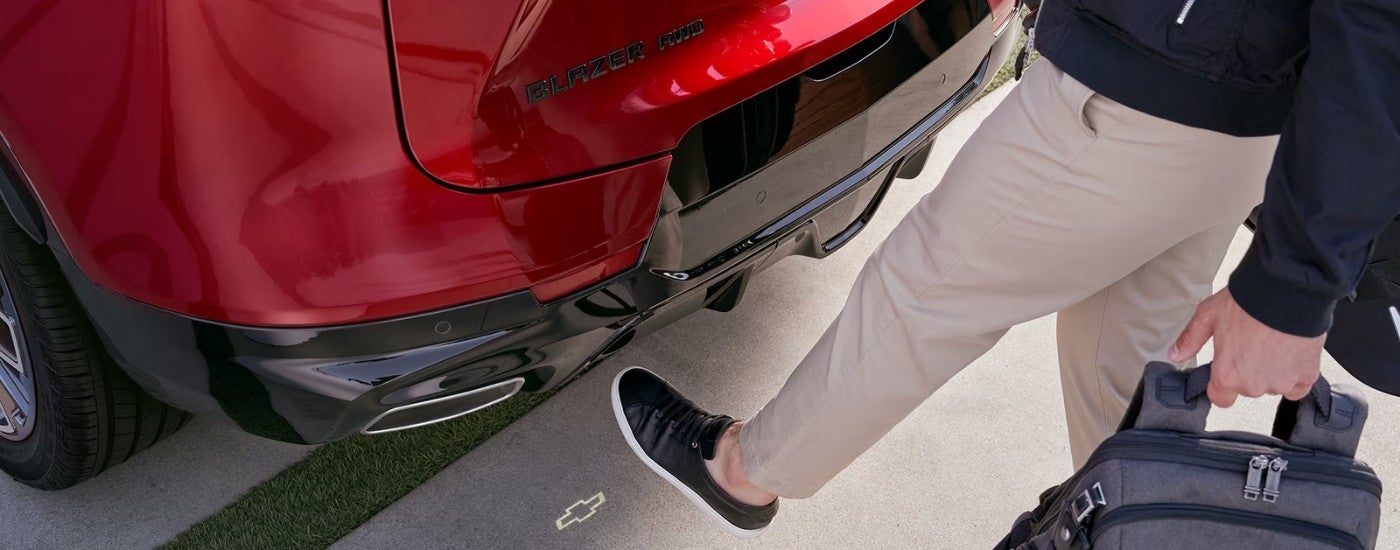 A person using the automatic rear cargo door on a red 2025 Chevy Blazer RS.