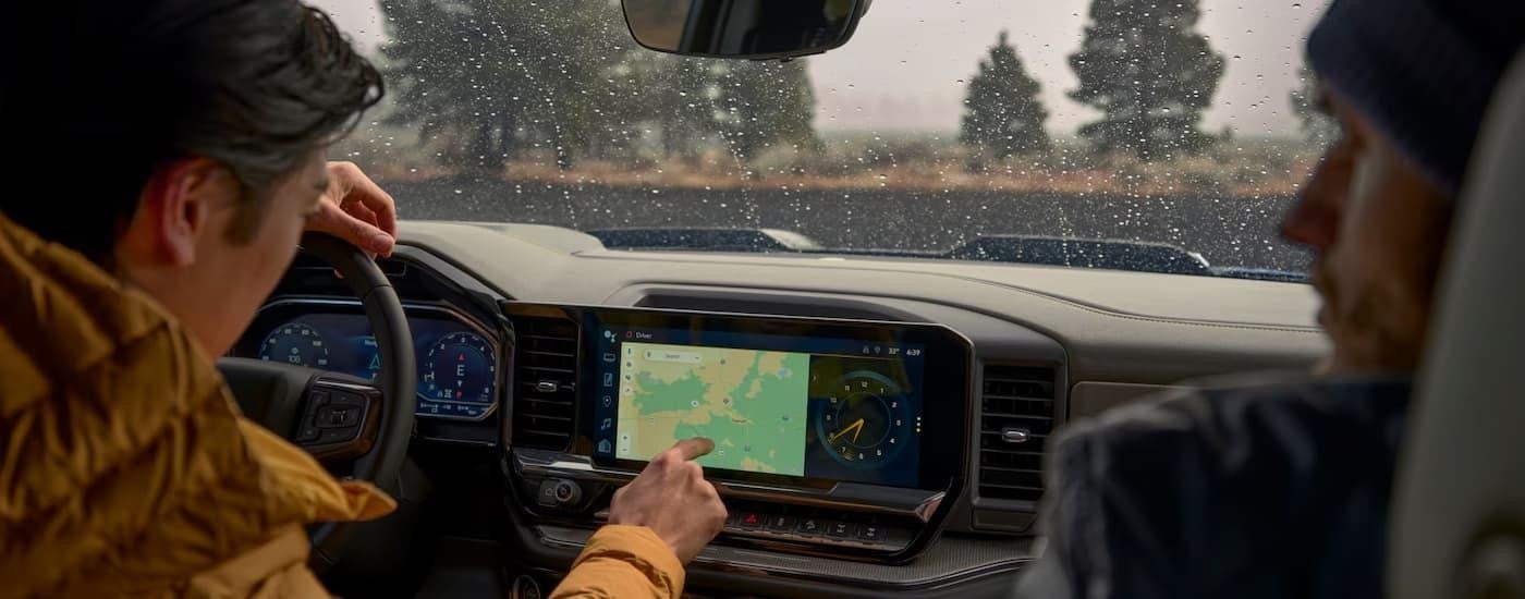 Two people are using the infotainment map screen in a 2025 Chevy Silverado 1500.