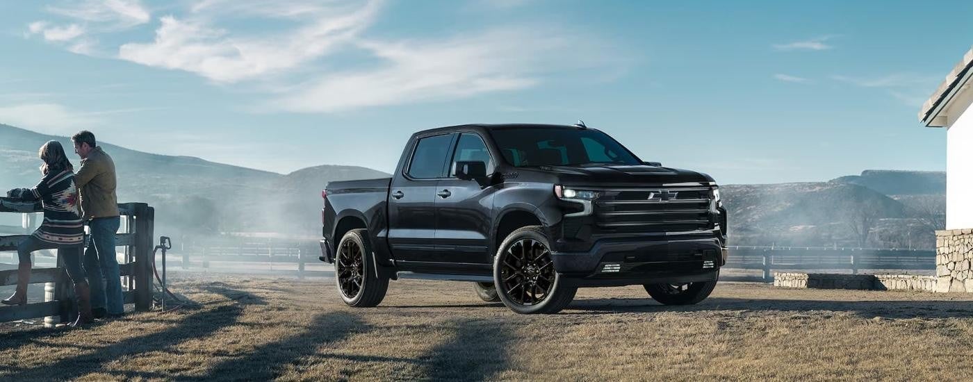 A black 2025 Chevy Silverado 1500 High Country is parked on a farm.
