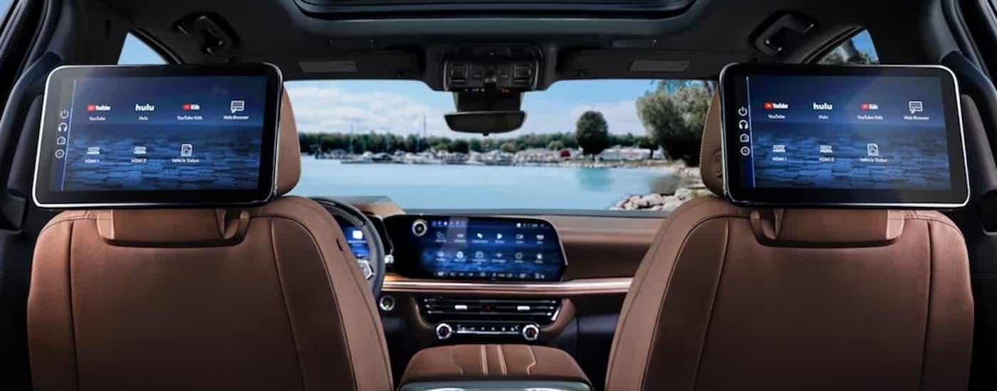 The brown interior of a 2025 Chevy Suburban shows the rear entertainment screens.