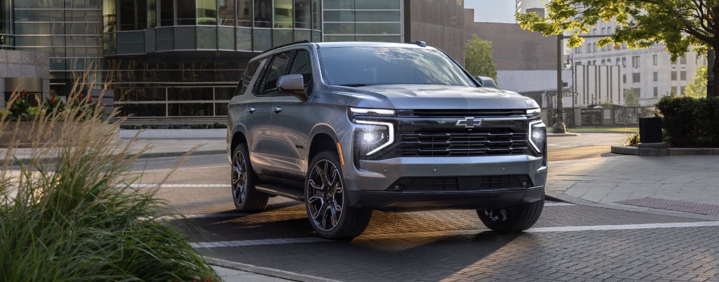 A silver 2025 Chevy Tahoe RST driving on a empty city street.