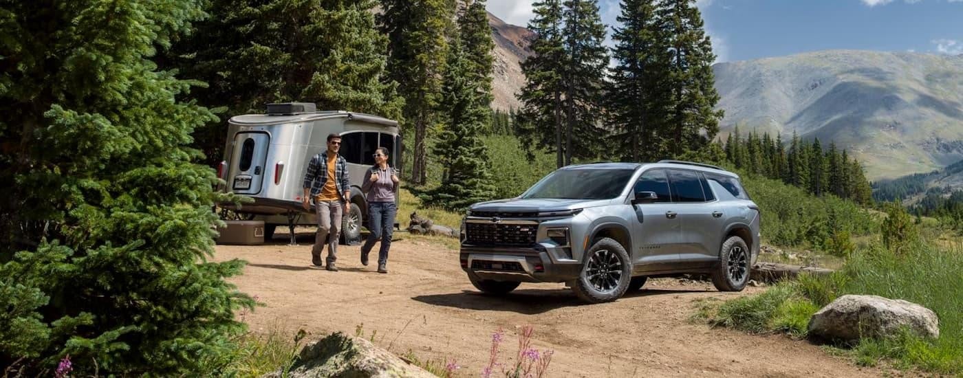 A grey 2025 Chevy Traverse Z71 is parked on dirt road near a remote camping area.