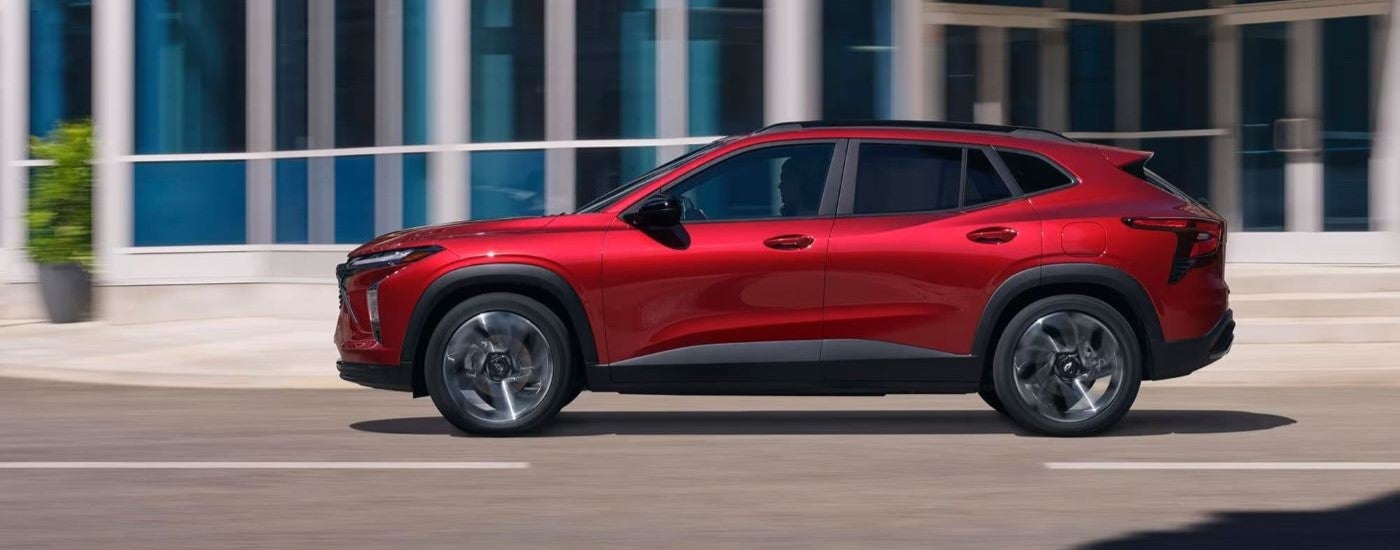 A red 2025 Chevy Trax RS driving on a city street.
